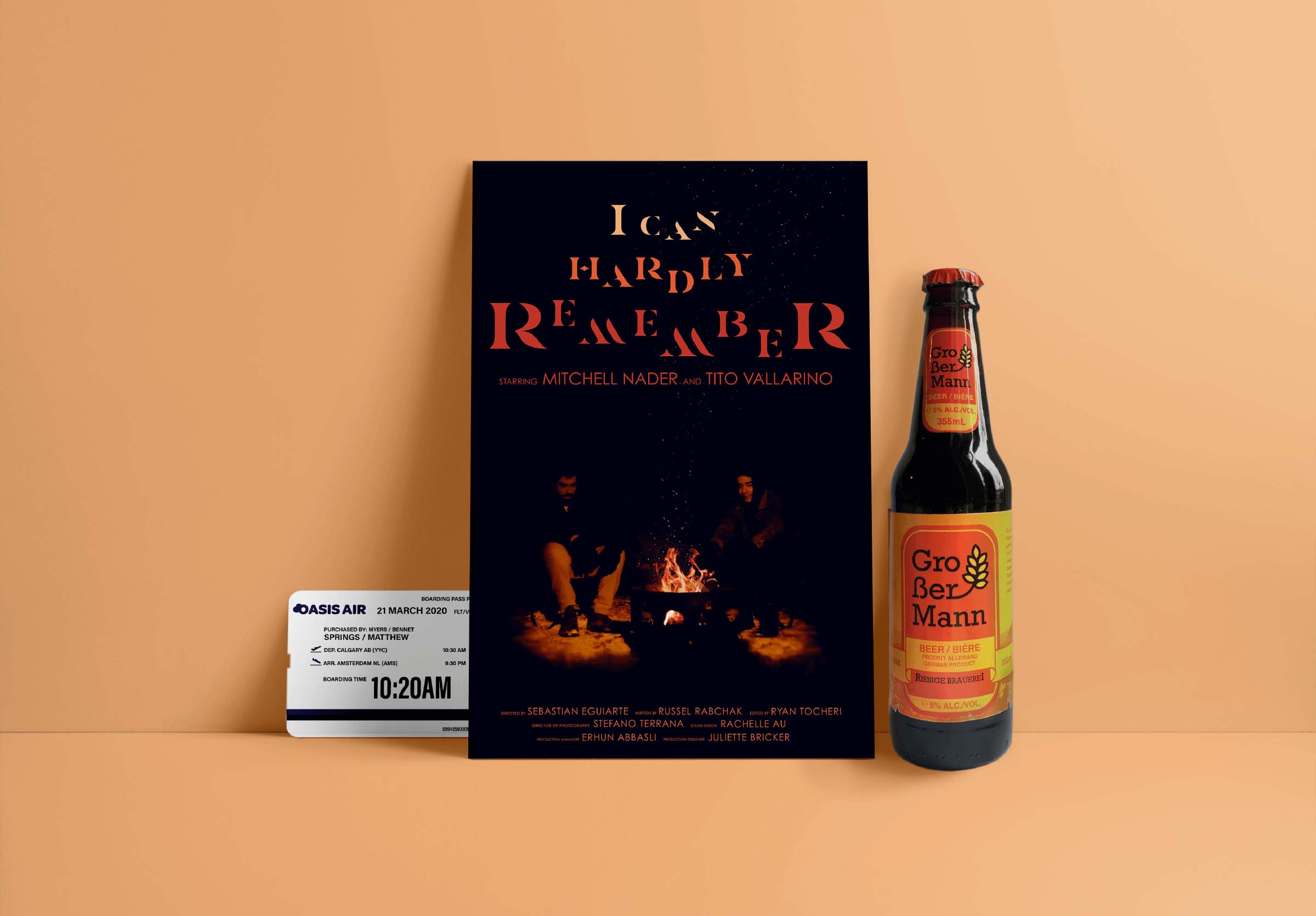 A dark movie poster of two guys sitting around a campfire and a plane ticket and beer bottle beside the poster